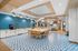 Modern communal space featuring a stylish dining area with blue geometric flooring, ambient pendant lighting, and a sleek kitchen counter with attractive tiling.