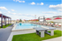 Luxurious rooftop pool area featuring sun loungers, shaded cabanas, and a ping pong table with a vibrant city view.