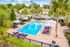 Luxurious outdoor swimming pool area with palm trees, sun loungers, and umbrellas, perfect for relaxation and enjoying sunny days.