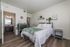 Inviting bedroom with elegant decor, featuring a soft bed with a plush green throw, stylish wood flooring, and an en-suite bathroom enhancing comfort and convenience.