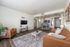Inviting open-plan living area with modern decor, featuring cozy seating, a stylish coffee table, and a sleek dining space under elegant lighting.