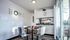 Bright dining area with a glass table set for four, adjacent to a modern kitchen with stainless steel appliances.