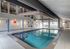 Modern indoor swimming pool with elegant design, featuring large windows and ample lighting.