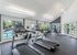 Bright and modern gym with treadmills, weights, and large windows overlooking a pool.