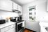 Bright and modern kitchen with sleek white cabinetry, stainless steel appliances, and natural light from a window.
