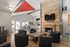 Modern communal living area featuring chic seating, a rustic fireplace, and a vibrant red ceiling accent.