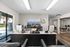 Inviting and modern office space featuring sleek black leather chairs, minimalist desks with computers, and a scenic landscape artwork, all bathed in natural light from large windows.