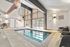 Inviting indoor pool area with natural light, modern seating, and stylish lighting.