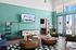 Bright and welcoming lounge area with stylish furniture, green accent wall, and large windows.