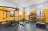 Contemporary fitness room with TRX equipment, kettlebells, and bright yellow walls.