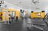 Modern gym with various fitness equipment, yellow walls, and ample open space.