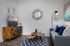Chic living room with stylish decor featuring a modern sofa, geometric rug, wooden TV stand with accent cabinet doors, and contemporary artwork.