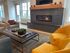 Modern, cozy living room with plush mustard chairs, stylish accent chairs, and a sleek tiled fireplace, perfect for relaxing.