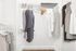 Organized walk-in closet with hanging clothes and shelves in a modern apartment.