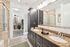Luxurious bathroom with granite countertop, dual sinks, and view of walk-in closet.