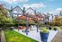 Inviting pergola with seating area and grill in a landscaped garden, surrounded by modern townhouses.