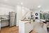 Chic open-concept kitchen and living room with luxury finishes and large windows overlooking lush greenery.