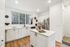 Bright, modern kitchen with white cabinets, hardwood floors, and stainless steel appliances.