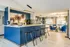 Bright open-concept kitchen with sleek bar stools and cozy living area, modern decor and large windows.