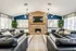 Elegant living room featuring dark leather sofas, a brick fireplace, and contemporary chandeliers.