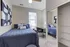 Inviting bedroom featuring a comfortable bed with blue bedding, abstract wall art, a desk, and a mirrored closet.