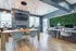 Bright co-working area with modern furnishings, stone fireplace, hanging lights, and lush greenery accent.