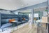 Modern co-working lounge with stylish blue seating, vibrant orange cushions, and sleek wooden flooring.