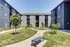 Modern apartment complex courtyard featuring landscaped greenery and a welcoming pathway.