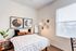 Contemporary bedroom with stylish decor, featuring a cozy bed, geometric wall art, and a bright window.
