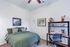 Inviting bedroom with a green bedspread, modern artwork, and a sleek desk area.