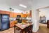 Bright kitchen with wooden cabinetry, sleek dining table, and adjacent modern office space.