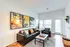 Bright and modern living room featuring stylish furniture, vibrant wall art, and large windows.