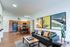 Bright modern living room with sleek furnishings, vibrant artwork, and a cozy open kitchen.
