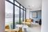 Inviting corner lounge with large windows, chic yellow armchairs, and contemporary wall art.