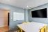 Stylish meeting room with a modern white table, yellow chairs, a mounted TV, and a large window.