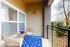 Inviting small balcony with wicker chairs and a vibrant blue rug, overlooking a scenic view.