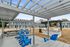 Inviting patio area with blue chairs and barbecue grills set under a pergola, with charming blue townhouses in the background.