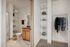 Modern bathroom with wooden cabinetry next to an open closet with shelving and hanging space.