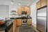 Modern kitchen with stainless steel appliances, sleek black countertops, and wooden cabinetry.