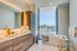 Luxurious bathroom with dual sinks, freestanding tub, and city view.