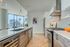 Modern kitchen with stylish cabinetry and state-of-the-art appliances, featuring large windows and a city view.