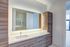 Contemporary bathroom with illuminated mirror, elegant wood cabinets, and designer fixtures.