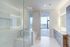 Bright and spacious bathroom with a glass shower, modern fixtures, and a cityscape view.