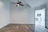 Spacious room with modern wooden flooring and a sleek ceiling fan, opening to a stylish kitchen.