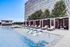 Elegant outdoor pool area with private cabanas and modern lounge chairs, set against a tall building.