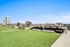 Vibrant rooftop terrace with lush green lawn and modern seating overlooking city skyline.