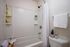 Contemporary bathroom featuring a clean white bathtub with elegant tiling and stylish accents.