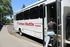 University Village campus shuttle with a person boarding, trees and signage visible.