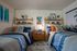 Inviting bedroom with twin beds, vibrant decor, and chic shelving for a modern touch.
