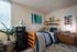 Charming bedroom with wooden bed, decorative artwork, and essential amenities in a well-lit space.